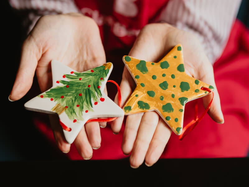 Hands holding two star-shaped Christmas decorations